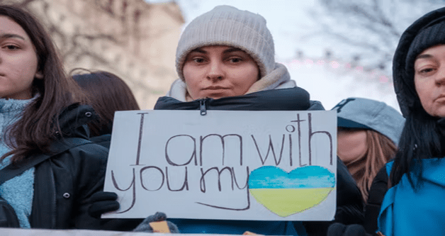 A woman holding up a sign that says " i am with you my heart ".