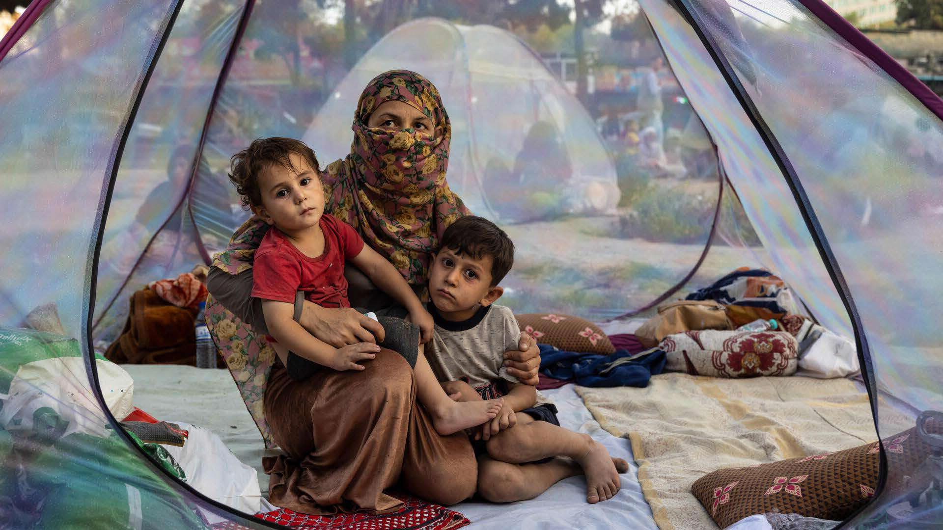 A woman and two children sitting under a tent.