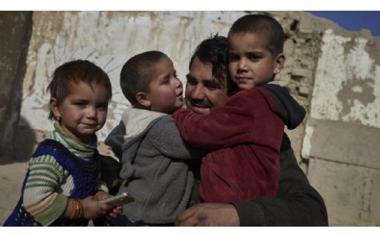 A man holding two young boys in his arms.