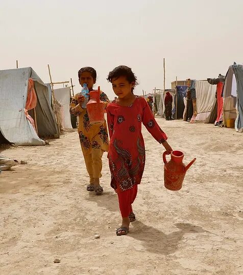 A young girl is walking with her mother in the desert.