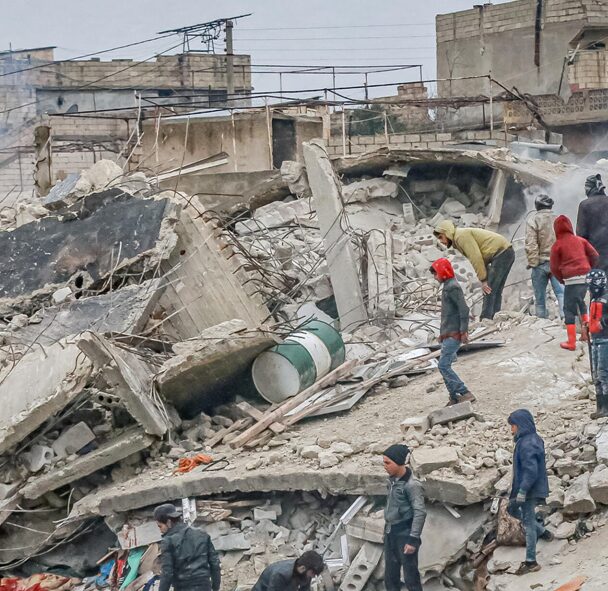 A group of people standing around rubble on the side of a road.