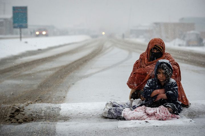 A woman and child sitting on the side of a road.