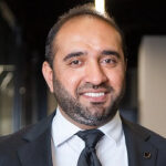 A man in a suit and tie smiling for the camera.